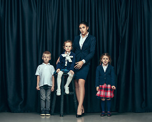 Image showing Cute stylish children on dark studio background. The beautiful teen girls and boy standing together