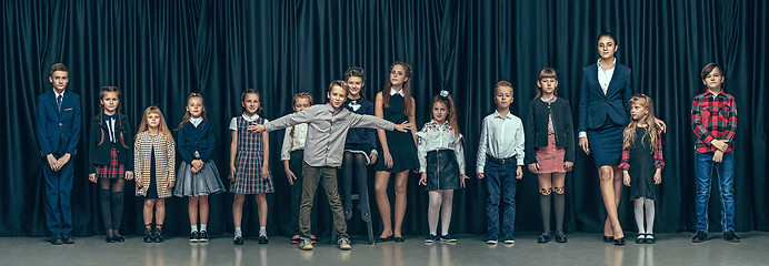 Image showing Cute stylish children on dark studio background. The beautiful teen girls and boy standing together