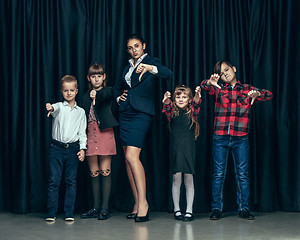 Image showing Cute stylish children on dark studio background. The beautiful teen girls and boy standing together