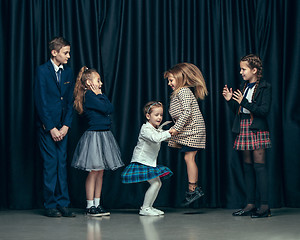 Image showing Cute stylish children on dark studio background. The beautiful teen girls and boy standing together