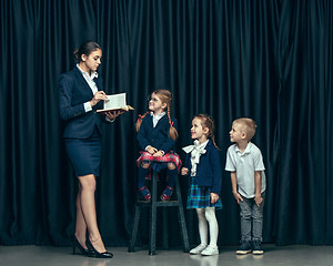 Image showing Cute stylish children on dark studio background. The beautiful teen girls and boy standing together