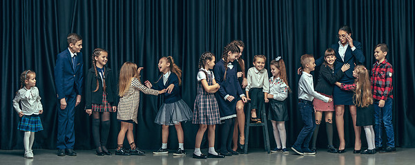 Image showing Cute stylish children on dark studio background. The beautiful teen girls and boy standing together