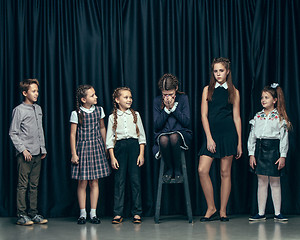 Image showing Cute stylish children on dark studio background. The beautiful teen girls and boy standing together