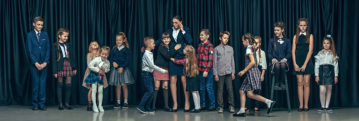 Image showing Cute stylish children on dark studio background. The beautiful teen girls and boy standing together