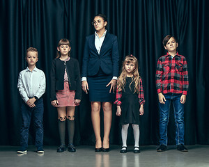 Image showing Cute stylish children on dark studio background. The beautiful teen girls and boy standing together