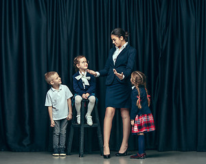 Image showing Cute stylish children on dark studio background. The beautiful teen girls and boy standing together