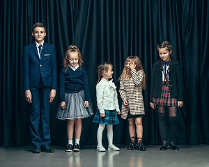 Image showing Cute stylish children on dark studio background. The beautiful teen girls and boy standing together