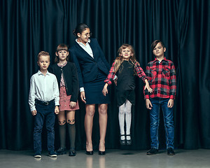 Image showing Cute stylish children on dark studio background. The beautiful teen girls and boy standing together