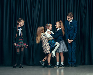 Image showing Cute stylish children on dark studio background. The beautiful teen girls and boy standing together