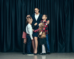 Image showing Cute stylish children on dark studio background. The beautiful teen girls and boy standing together