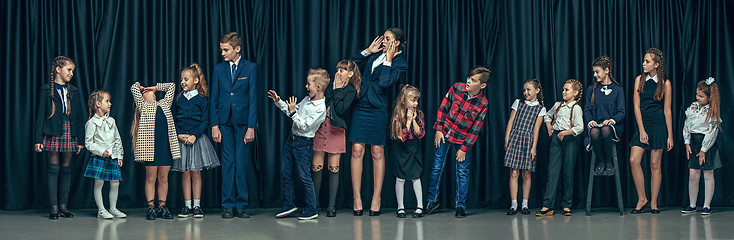 Image showing Cute stylish children on dark studio background. The beautiful teen girls and boy standing together