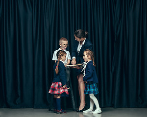 Image showing Cute stylish children on dark studio background. The beautiful teen girls and boy standing together