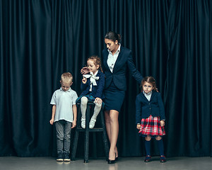 Image showing Cute stylish children on dark studio background. The beautiful teen girls and boy standing together