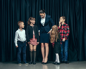 Image showing Cute stylish children on dark studio background. The beautiful teen girls and boy standing together