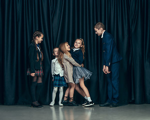 Image showing Cute stylish children on dark studio background. The beautiful teen girls and boy standing together