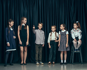 Image showing Cute stylish children on dark studio background. The beautiful teen girls and boy standing together