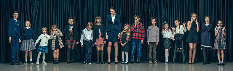 Image showing Cute stylish children on dark studio background. The beautiful teen girls and boy standing together