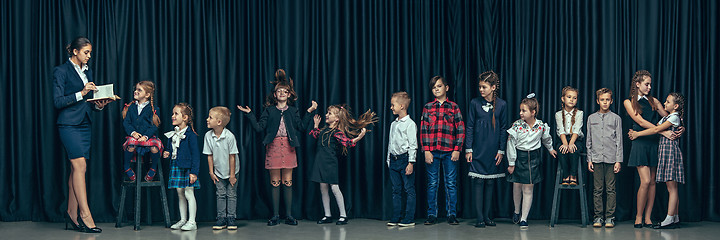 Image showing Cute stylish children on dark studio background. The beautiful teen girls and boy standing together