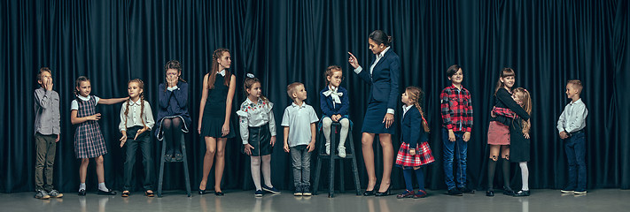 Image showing Cute stylish children on dark studio background. The beautiful teen girls and boy standing together