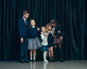 Image showing Cute stylish children on dark studio background. The beautiful teen girls and boy standing together