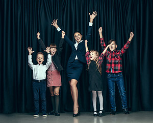 Image showing Cute stylish children on dark studio background. The beautiful teen girls and boy standing together