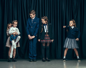 Image showing Cute stylish children on dark studio background. The beautiful teen girls and boy standing together