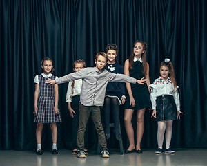 Image showing Cute stylish children on dark studio background. The beautiful teen girls and boy standing together