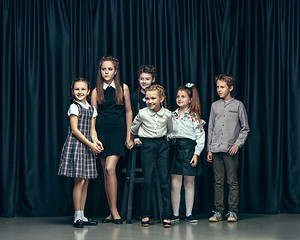 Image showing Cute stylish children on dark studio background. The beautiful teen girls and boy standing together