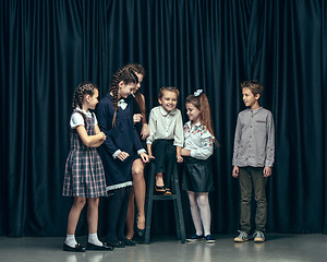 Image showing Cute stylish children on dark studio background. The beautiful teen girls and boy standing together