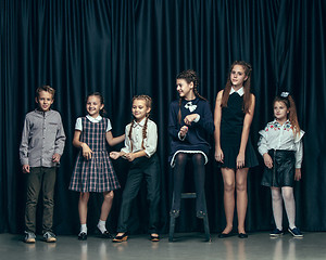 Image showing Cute stylish children on dark studio background. The beautiful teen girls and boy standing together