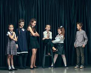 Image showing Cute stylish children on dark studio background. The beautiful teen girls and boy standing together