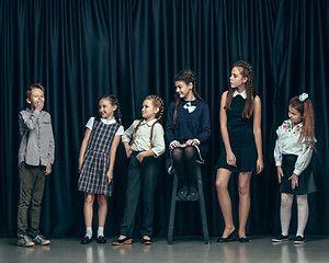 Image showing Cute stylish children on dark studio background. The beautiful teen girls and boy standing together