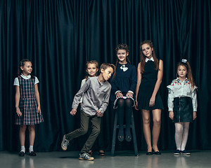 Image showing Cute stylish children on dark studio background. The beautiful teen girls and boy standing together