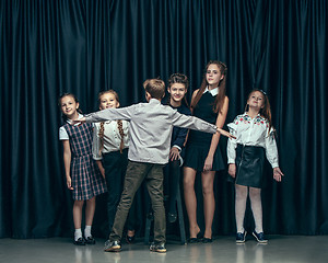 Image showing Cute stylish children on dark studio background. The beautiful teen girls and boy standing together