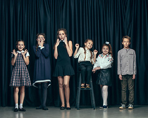 Image showing Cute stylish children on dark studio background. The beautiful teen girls and boy standing together