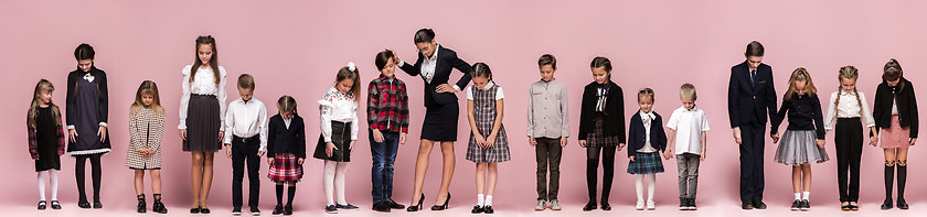 Image showing Cute stylish children on pink studio background. The beautiful teen girls and boy standing together