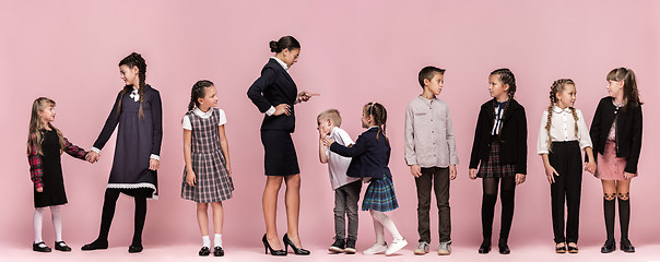 Image showing Cute stylish children on pink studio background. The beautiful teen girls and boy standing together