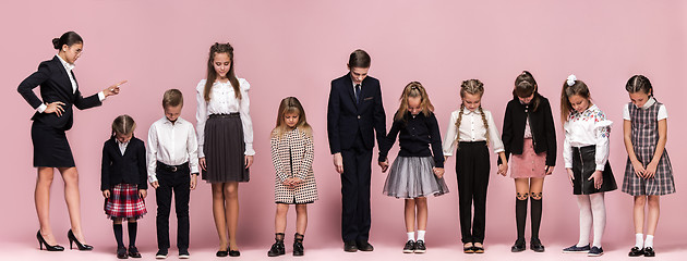 Image showing Cute stylish children on pink studio background. The beautiful teen girls and boy standing together