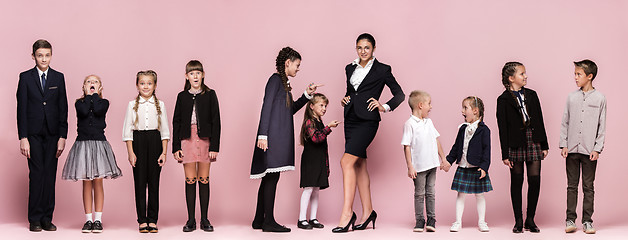 Image showing Cute stylish children on pink studio background. The beautiful teen girls and boy standing together