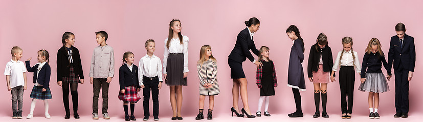 Image showing Cute stylish children on pink studio background. The beautiful teen girls and boy standing together