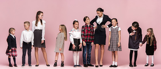 Image showing Cute stylish children on pink studio background. The beautiful teen girls and boy standing together