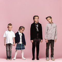 Image showing Cute stylish children on pink studio background. The beautiful teen girls and boy standing together