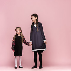 Image showing Cute stylish children on pink studio background. The beautiful teen girls standing together