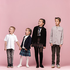 Image showing Cute stylish children on pink studio background. The beautiful teen girls and boy standing together