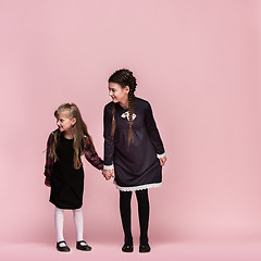 Image showing Cute stylish children on pink studio background. The beautiful teen girls standing together