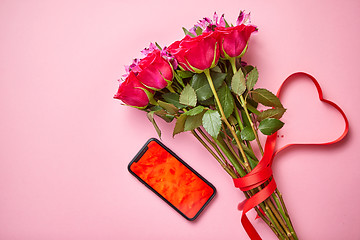 Image showing Pink roses bouquet with hart shaped bow and mobile phone with copy space screen