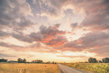 Image showing Rural sunset with an asphalt road crossing a countryside