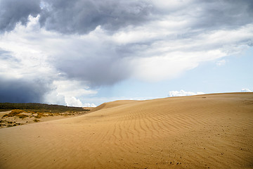 Image showing Sand dune in a desert with dark clouds