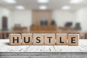 Image showing Hustle sign with text on a worn desk