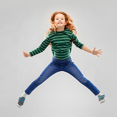 Image showing smiling red haired girl in striped shirt jumping